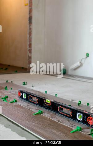 Tile levelling system, four plastic green clips with wedges. Close-up view, selective focus, blurred background. Stock Photo