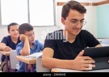 Teenager using the tablet in school and have a smile on his face Stock Photo