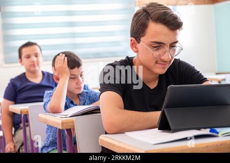 Teenager using the tablet in school and have a smile on his face Stock Photo