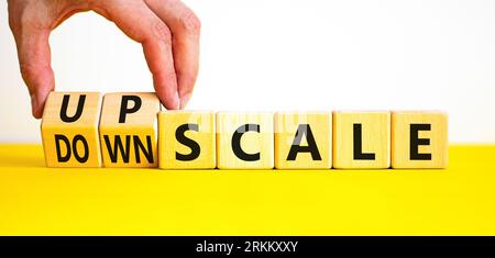 Upscale or downscale symbol. Concept words Upscale or Downscale on wooden cubes. Beautiful yellow table white background. Businessman hand. Business u Stock Photo