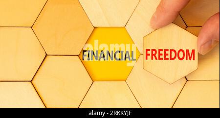 Financial freedom symbol. Concept words Financial freedom on beautiful wooden puzzles. Beautiful yellow paper background. Businessman hand. Business f Stock Photo