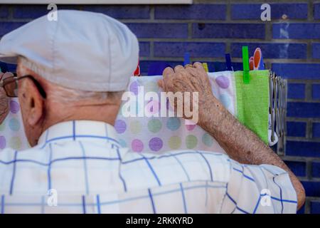 Active elderly doing household. Unrecognizable retired man hanging up the laundry. Cooperation, responsibility and equality in domestic life Stock Photo
