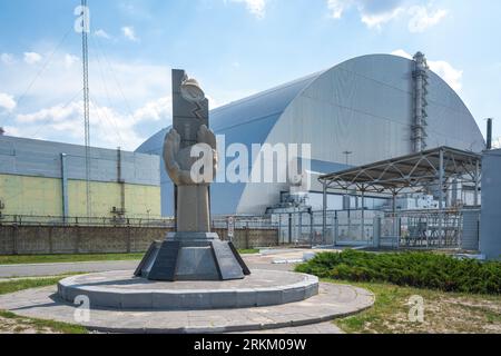 Monument to professionals who protected the world from nuclear disaster and Reactor 4 New Safe Confinement - Chernobyl Exclusion Zone, Ukraine Stock Photo