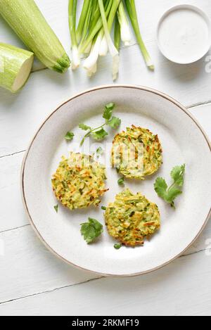 Zucchini fritters. Vegetable vegetarian zucchini pancakes on plate over white wooden background. Top view, flat lay Stock Photo
