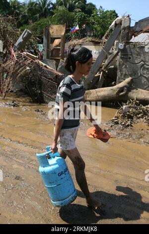 Bildnummer: 56772097  Datum: 21.12.2011  Copyright: imago/Xinhua (111221) -- MANILA, Dec. 21, 2011 (Xinhua) -- A girl carries a gas tank from her home that was damaged by the floods brought by tropical storm Washi in Cagayan de Oro, the Philippines on December 21, 2011. The Philippine government will release an additional 1 billion pesos (22.77 million U.S. dollars) funding to augment the remaining calamity fund and ensure swift and continuous assistance to the areas hit by storm Washi (local name: Sendong). (Xinhua/Rouelle Umali) (srb) PHILIPPINES--CAGAYAN DE ORO-TROPICAL STORM WASHI PUBLICAT Stock Photo