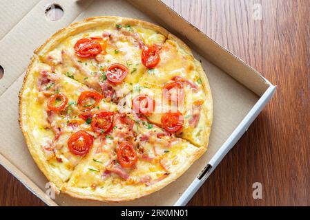 Small pizza in a cardboard box on the table. View from above. Stock Photo