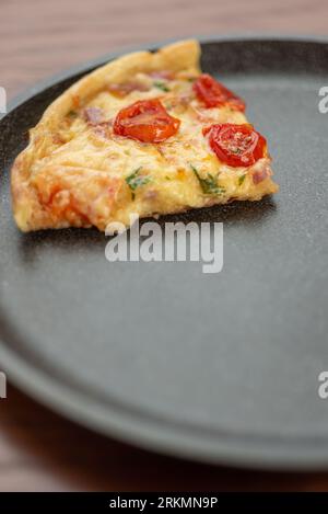 A piece of pizza on a dark frying pan. Stock Photo