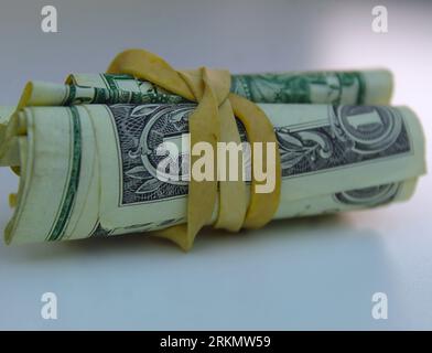 A photo of several bank notes rolled up in a yellow elastic band. Stock Photo