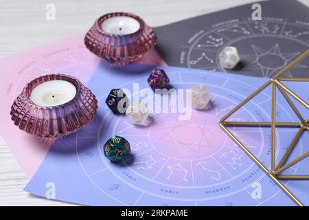 Zodiac wheels, astrology dices and burning candles on table, closeup Stock Photo