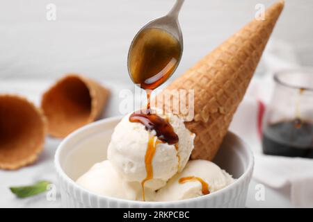 Pouring caramel sauce onto ice cream on table, closeup Stock Photo