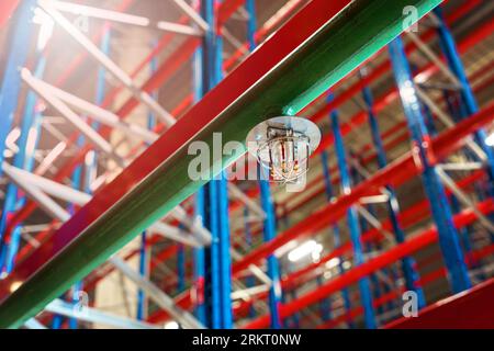 Fire sprinkler in a large warehouse with metal shelving Stock Photo