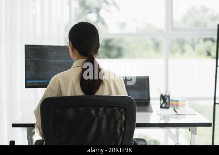 Back of developer programmer programming code to developing web and application in software office. Stock Photo