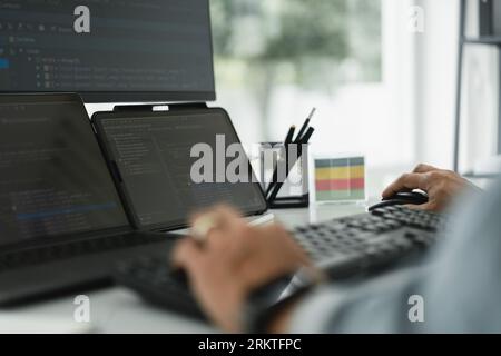 Developer programmer checking code on multiple monitor while programming to developing web and apps. Stock Photo