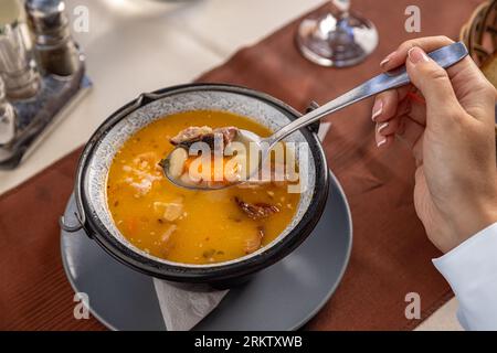 Traditional homemade bean soup with smoked pork meat served in small cauldron Stock Photo