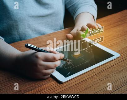 Woman writing or tick correct mark to approve document or project on digital tablet. Evaluation form, questionnaire, acceptance, approval, signing. Stock Photo