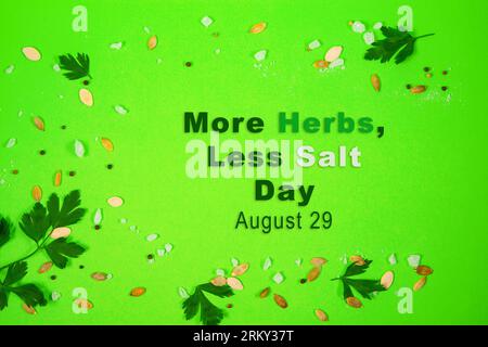 Bold and striking green background with herbs, coarse salt, pumpkin seeds and peppercorns. Poster to More Herbs, Less Salt Day observed on August 29 Stock Photo