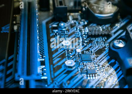 Motherboard with sockets and microchips close-up on modern powerful desktop PC in blue light. Computer hardware chipset components. Tech industry elec Stock Photo