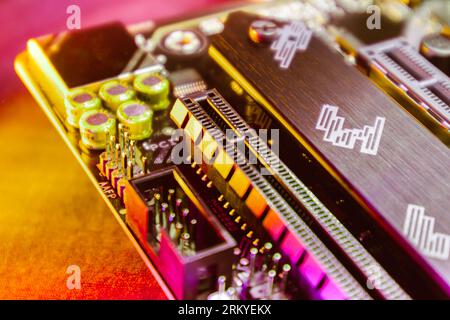 Motherboard with sockets and microchips close-up on desktop PC in colorful vivid light. Computer hardware chipset components. Tech industry electronic Stock Photo