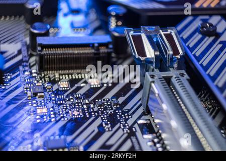 Motherboard with sockets and microchips close-up on modern powerful desktop PC. Computer hardware components in blue light. Tech industry background Stock Photo