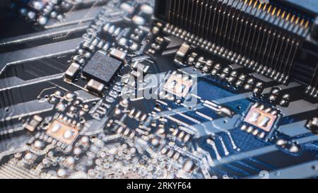 Motherboard with microchips close-up on modern powerful desktop PC. Computer hardware chipset components background with blue light Stock Photo