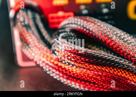 Wiring on power supply unit of desktop PC close-up with selective focus. Computer cables hardware components background in red color light Stock Photo