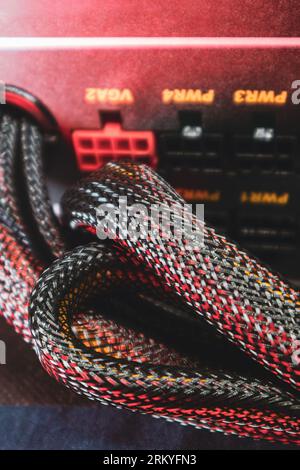 Power supply unit with wires, desktop PC parts close-up with selective focus. Computer cables hardware components background in red color light Stock Photo
