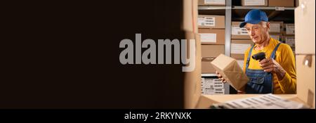 Senior male worker scanning barcode on delivery parcel. Worker scan barcode of cardboard packages before delivery at storage. Stock Photo