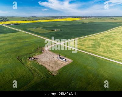 Aerial oil and gas well at crossroads overlooking agriculture fields on the Canadian prairies in Alberta Canada. Stock Photo