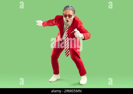 Full-size photo of a handsome bearded guy in the studio on a green background. Stock Photo