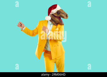 Freaky man with dinosaur head wearing santa hat having fun, happy and dancing at christmas party. Stock Photo