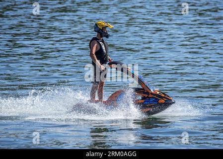 Jet skier riding jet ski / jetski / water scooter / stand-up personal watercraft / PWC on lake Stock Photo