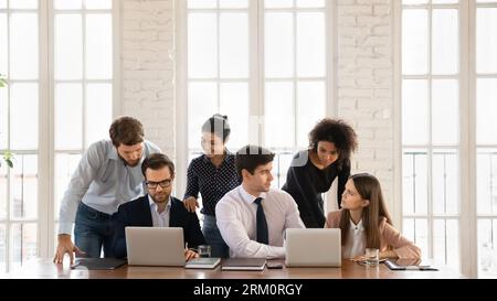 Smiling multiracial employees cooperate using laptops in office Stock Photo