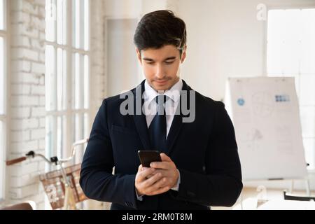 Young Caucasian businessman using smartphone in office Stock Photo