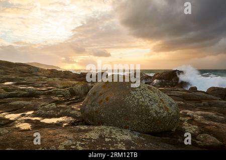 Rocky coastline of Costa da Morte coast with rough sea and breaking waves at sunset (Muxía, Fisterra, A Coruña, Galicia, Atlantic Sea, Spain) Stock Photo