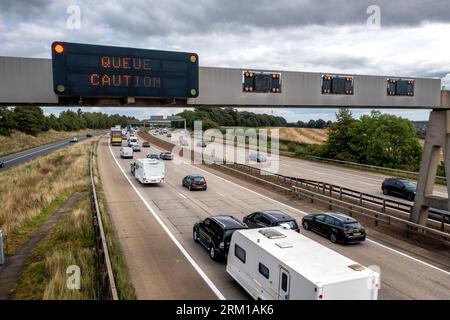 LEEDS, UK - AUGUST 25, 2023.  An overhead warning sign on a busy UK managed motorway warning motorists to reduce speed and take caution because of a q Stock Photo