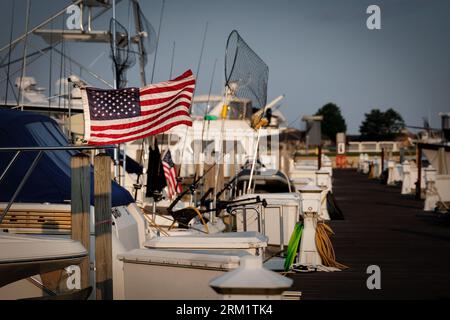 The sun rises on an American flag on the back of a boat in the harbor at Ludington, Michigan. Stock Photo