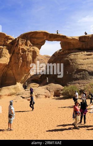 Tourists at the Burdah rock bridge, Wadi Rum, Unesco World Heritage Site, Jordan, Middle East Stock Photo