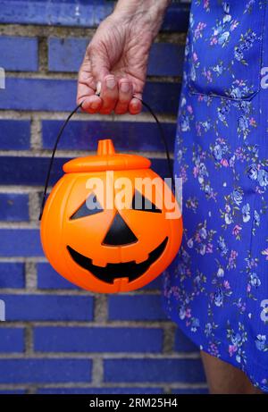 Close-up of a senior woman holding orange halloween pumpkin on day of the dead. Tradition of jack-o-lantern Stock Photo