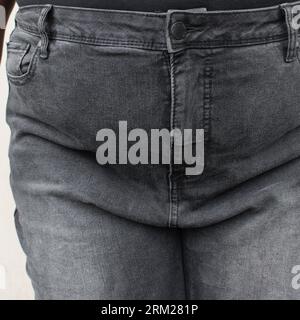 Overweight woman in jeans, woman with a fat upper pubic area in jean trousers, A plus size girl with fupa in high waist denim trousers Stock Photo