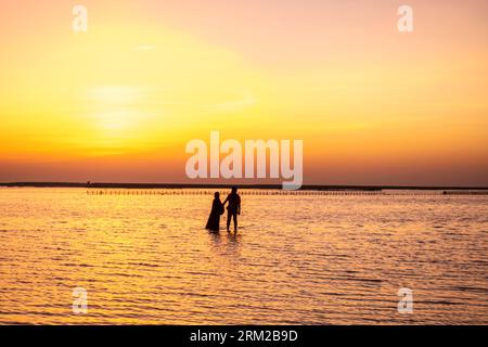 A couple, man and woman walking in shallow water,  Bahrain Al-Seef, Karbabad beach Stock Photo