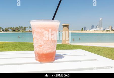 Peach drink with ice and straw with a view of tropical shore coast in Bahrain Middle East Stock Photo