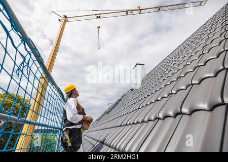 roofer on construction site operating crane Stock Photo