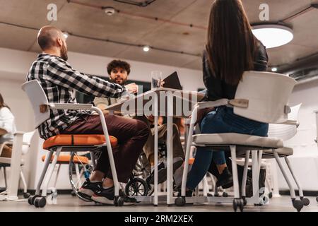 Business learning concept. Young business team gathered at table discussing new business ideas, sharing knowledge and planning new strategy. Stock Photo