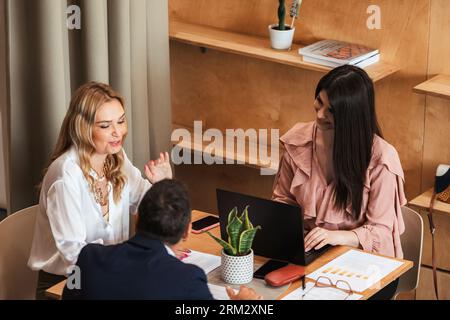 Three work colleagues working and talking at the cafe bar Stock Photo