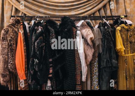 Women's evening long dresses and fur coats hanging on hangers on the fashion backstage in the vintage interior Stock Photo