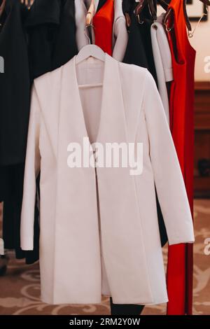 Women's white classy jacket hanging on the fashion backstage. Vertical Stock Photo