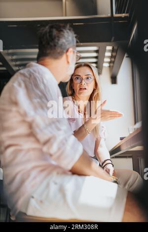 Diverse business partners collaborating for success. Businesswoman gesturing and explaining serious business problems at their company to her male par Stock Photo
