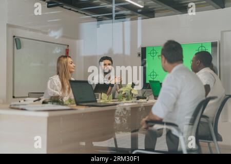 A diverse team of businesspeople collaborating in an office workspace, discussing and analyzing data to achieve profit growth and project development. Stock Photo