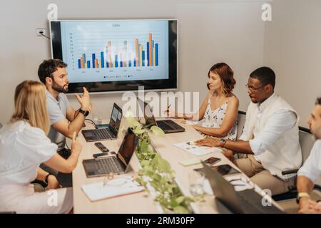 A diverse group of business employees in an office, analyzing statistics, discussing profit growth, and collaborating on project development and marke Stock Photo