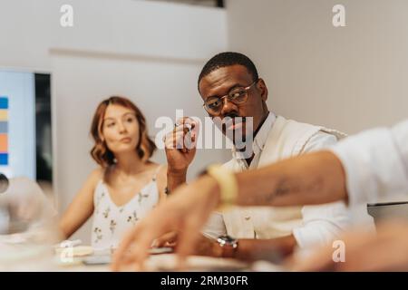 A diverse business team analyzing statistics, planning project development, and discussing profit growth in an indoor office space. Stock Photo